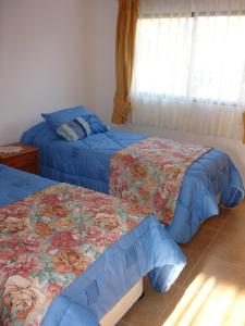 安加罗阿Turismo Vinapu的一间卧室配有两张蓝色床罩和窗户。