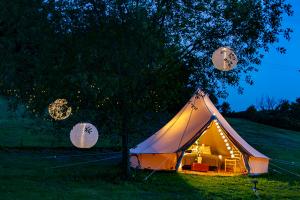 切斯特Lloyds Meadow Glamping的夜晚在田野里带一张沙发的帐篷