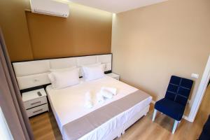 吉诺卡斯特Brilant Luxury Apartment的卧室配有白色的床和蓝色椅子