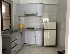 峇都丁宜斯里萨阳度假服务式公寓酒店的厨房配有白色橱柜和冰箱。