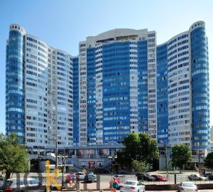 敖德萨Greendoor Arcadia的一座大型蓝色建筑,停车场内有汽车