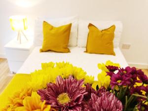 曼彻斯特Ekhaya three的一张带黄色枕头和一束鲜花的床
