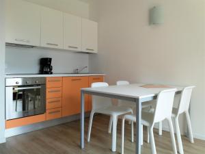 加尔达湖滨Appartamenti Garda il lago的厨房配有桌子和一些白色的椅子