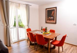 比耶拉Apartments Balbo的一间带木桌和红色椅子的用餐室