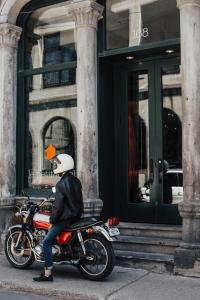 蒙特利尔Le Petit Hotel St Paul by Gray Collection的坐在建筑物前的摩托车上的人