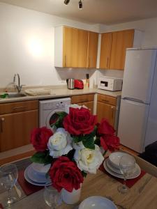 巴塞尔顿Vetrelax Basildon Crosse Apartment的厨房配有红色和白色玫瑰花桌
