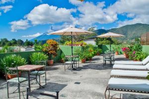 危地马拉安地瓜Posada San Vicente by AHS的庭院里摆放着一排桌椅和遮阳伞