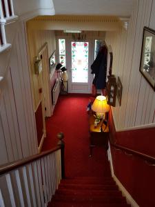 凯西克多切斯特楼酒店的一条铺有红地毯的走廊和一扇带灯的门