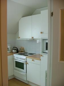 赫讷Klovabo Bed & Breakfast的厨房配有白色橱柜和炉灶烤箱。