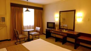 马尼拉罗斯曼酒店的酒店客房带一张床、一张书桌和一面镜子