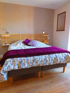 图尔尼LA MAISON DE MARION的卧室内的一张带紫色棉被的床