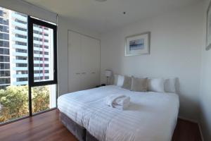 墨尔本ACD Apartments的卧室设有白色的床和大窗户