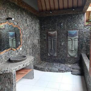 佩母德兰巴厘岛佩母得兰芙蓉住宿加早餐旅馆的一间设有石墙的房间,上面有雕像
