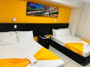 瓜达拉哈拉Hotel Belisario INN的酒店客房设有两张床,墙上挂有绘画作品