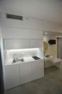 米西姆纳Olive Press Hotel & Apartments的厨房配有白色橱柜和水槽