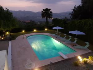 费尔盖拉什Casa de Ladrido的游泳池在晚上提供椅子和遮阳伞