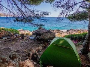 希马拉THE SEA CAVE CAMPING的海边岩石海滩上的绿色帐篷