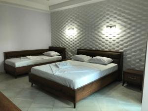 乌雷基Magnetiti Hotel的卧室内的两张床,墙上有两盏灯