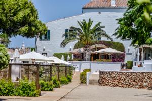埃斯卡斯特利Hotel Rural Sant Joan de Binissaida的一座带围栏和遮阳伞的白色建筑