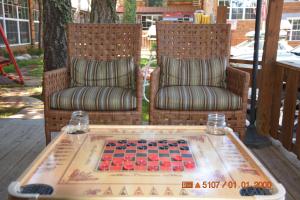 鲁伊多索斯马克木屋旅馆的门廊上的桌子上放着两把椅子和棋盘