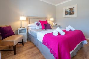 罗斯莱尔Coral Gables Guesthouse & Campsite的一间卧室配有两张床、粉色床单和椅子
