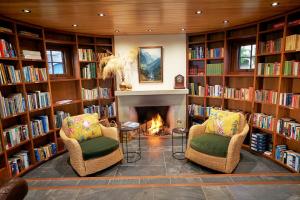 马纳普里Cabot Lodge - Fiordland National Park的图书馆配有两把椅子和壁炉