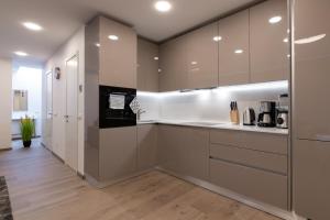 塔林Central Lootsi Penthouse的厨房配有棕色和白色的橱柜,铺有木地板