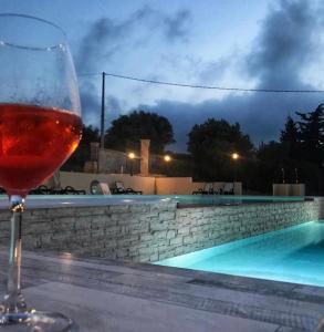 阿格里真托Agriturismo La Casa di Bacco的坐在游泳池旁的桌子上喝一杯葡萄酒