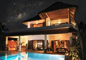 江比阿Joya' Beach Suites & Villa的夜间带游泳池的别墅