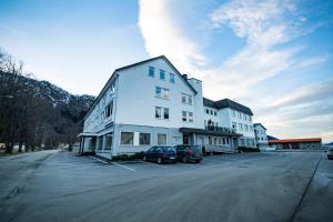 努尔菲尤尔埃德Nordfjord Hotell - Bryggen的一座白色的大建筑,汽车停在停车场