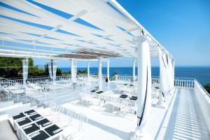 VatopediBianco Olympico Beach Resort-All Inclusive的一个带白色桌椅的甲板和大海