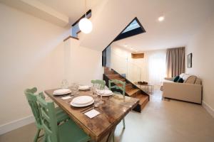 卡塞雷斯Apartamentos Habitavit en Cáceres的用餐室以及带木桌和椅子的客厅。