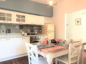 锡耶纳THE BLUE LODGE-cozy flat close to Piazza del Campo的一间带木桌的厨房和一间带白色橱柜的厨房