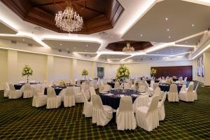 恩塞纳达港圣尼古拉斯赌场酒店的宴会厅配有白色的桌子和白色的椅子