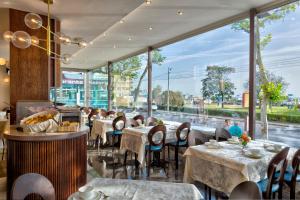 里米尼Hotel Vistamare的餐厅设有桌椅和大窗户。