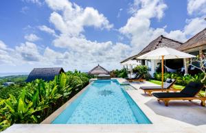 乌鲁瓦图曼陀罗村阳光屋度假村的别墅的游泳池配有椅子和遮阳伞