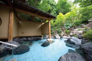 大津Ogoto Onsen Yunoyado Komolebi的一座有岩石和建筑的水池