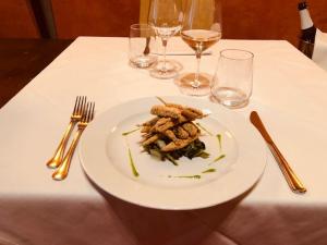 拉文纳凯佩罗酒店的桌上的白盘食物,配酒杯