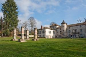 Olliergues尚特劳兹城堡酒店的一座有柱子的老房子,在前面的草地上