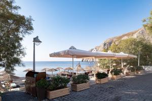 卡马利Santorini Crystal Blue Boutique Hotel的海滩上设有遮阳伞和椅子,还有大海