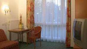 萨尔贝克斯提格曼酒店餐厅的一间设有桌子、电视和窗帘的房间