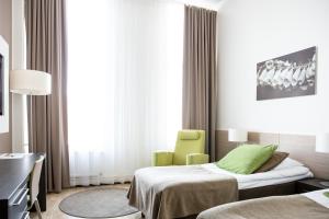 坦佩雷Norlandia Tampere Hotel的一间医院间,配有两张床和一把绿色椅子