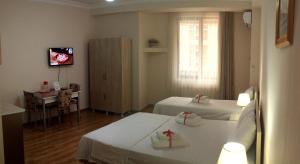 巴统Hotel Tao的客房设有两张床、一张桌子和电视。