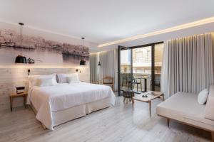 海若克利欧伊拉克利翁中心宜必思尚品酒店的卧室配有一张白色的大床和一张沙发。