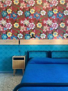 佛罗伦萨Ostello Tasso的一间卧室配有蓝色的床和花卉壁纸