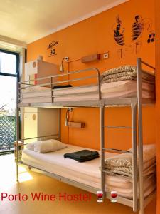 波尔图波尔图葡萄酒旅馆的橙色墙壁的客房内设有两张双层床。