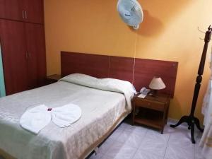 莫科阿Hotel Marli Plaza的一间卧室配有一张带风扇和床头柜的床。