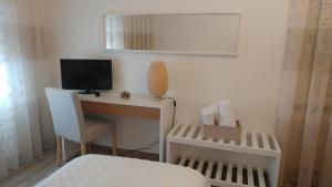 纳扎雷Casinha D'Avó的一间卧室配有一张桌子、一台电视和一张床