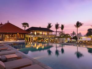 勒吉安巴厘尼克莎玛海滩精品度假酒店的一座带椅子的度假游泳池以及一座建筑