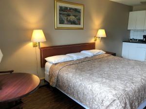 卡尔加里Travellers Inn的酒店客房配有一张床铺和一张桌子。